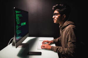 A Junior Python Developer working on desktop computer at white desk in office.