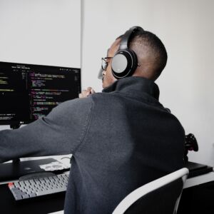 A Node.js Developer with headphones sitting at a computer, working remotely on a project.