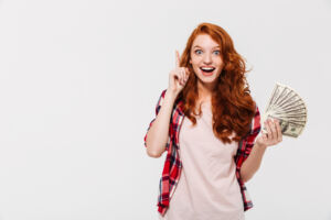 How to make money fast? A woman with ginger hair holding a lot of banknotes.