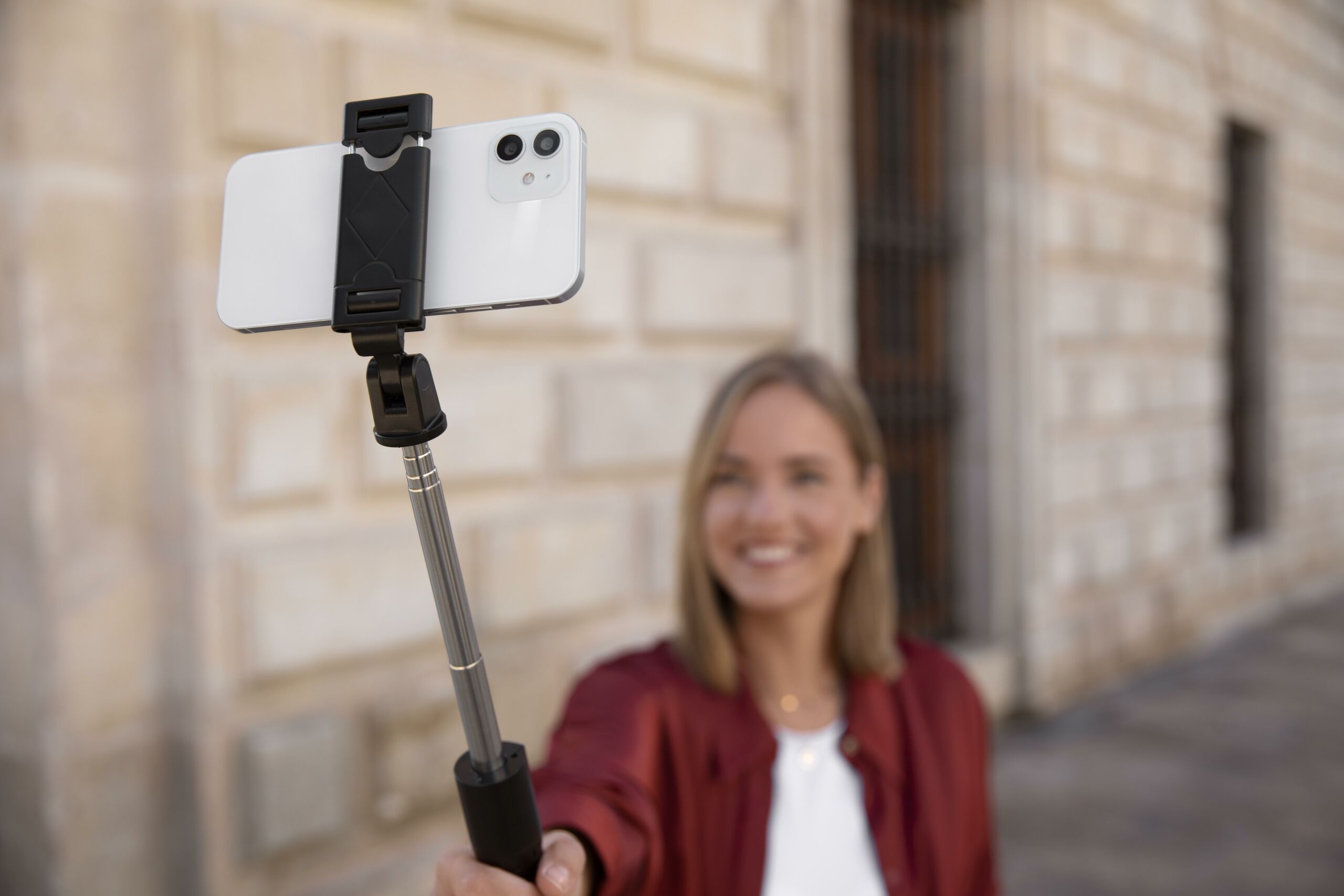 A phone gimbal. A woman holding a smartphone gimbal and filming herself on the street.